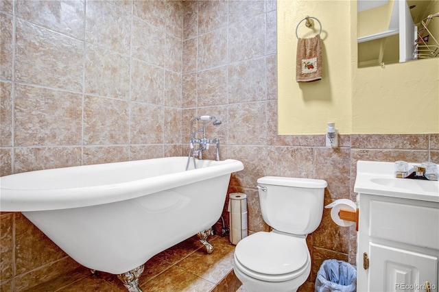 bathroom with toilet, tile patterned flooring, a freestanding bath, vanity, and tile walls