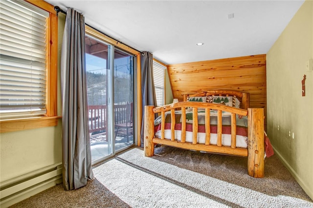 bedroom with wood walls, a baseboard radiator, carpet flooring, and access to exterior