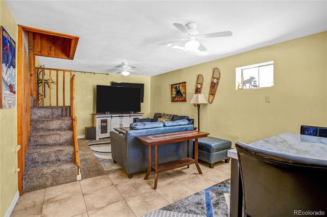 living area with light tile patterned floors, stairway, a ceiling fan, and baseboards