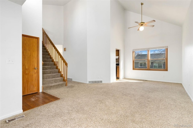 unfurnished living room with ceiling fan, carpet flooring, and high vaulted ceiling