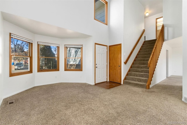 carpeted entrance foyer featuring a towering ceiling