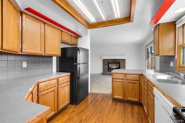 kitchen with sink, dishwasher, tasteful backsplash, light hardwood / wood-style floors, and black fridge