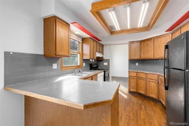 kitchen with sink, hardwood / wood-style flooring, black fridge, stainless steel electric stove, and kitchen peninsula