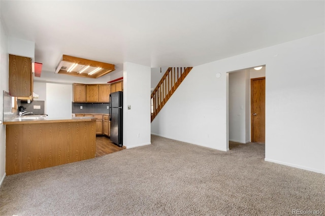 kitchen with black refrigerator, decorative backsplash, kitchen peninsula, and carpet