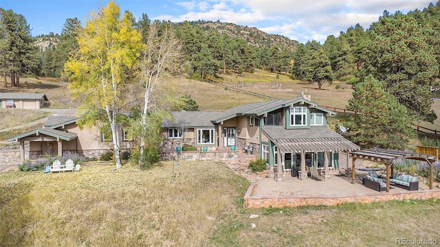 rear view of property featuring a patio area, a yard, and a pergola