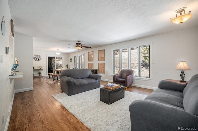 living room featuring ceiling fan, wood-type flooring, and a textured ceiling