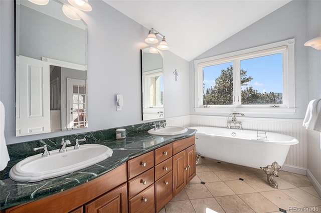 bathroom with tile patterned floors, a tub, vaulted ceiling, and vanity