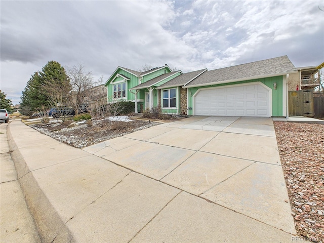 view of front facade with an attached garage, driveway, and fence