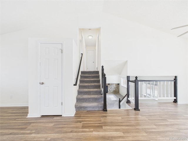 stairway with baseboards, lofted ceiling, and wood finished floors