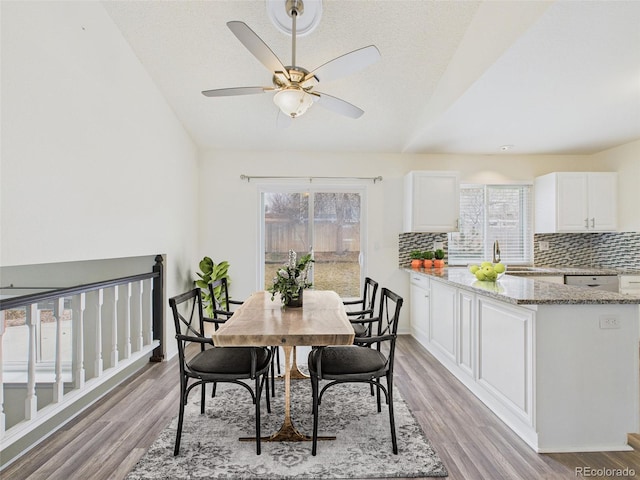 dining room featuring plenty of natural light, ceiling fan, light wood-style floors, and lofted ceiling