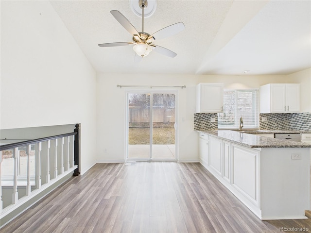 kitchen with light stone counters, white cabinets, tasteful backsplash, and light wood-type flooring