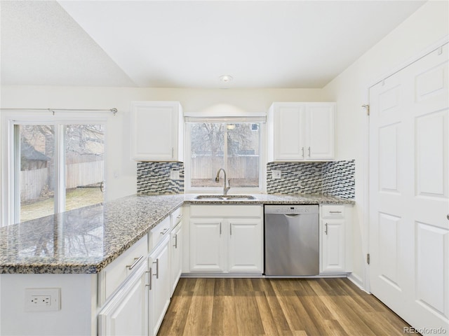 kitchen with wood finished floors, light stone countertops, a peninsula, a sink, and dishwasher