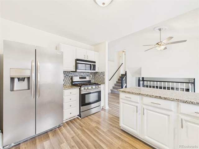 kitchen featuring white cabinetry, backsplash, light wood finished floors, and appliances with stainless steel finishes