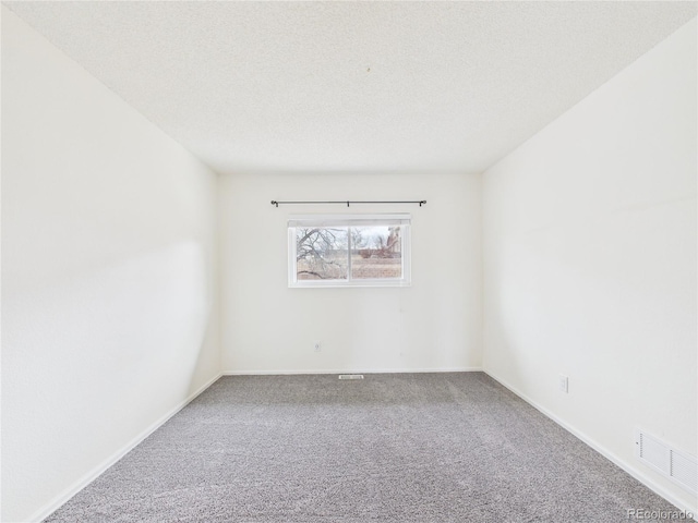 unfurnished room featuring visible vents, carpet floors, a textured ceiling, and baseboards