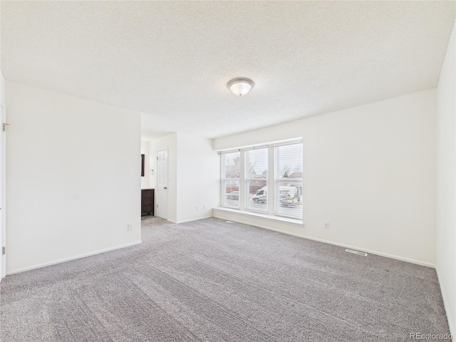 carpeted empty room featuring baseboards and a textured ceiling