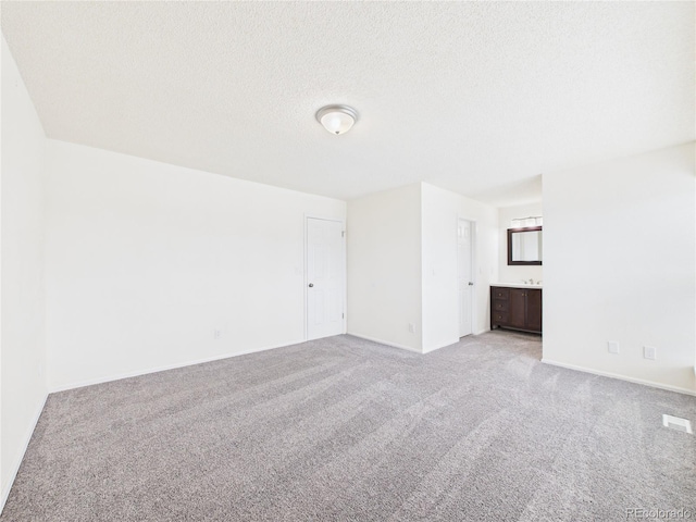 unfurnished room with a textured ceiling, baseboards, and light carpet