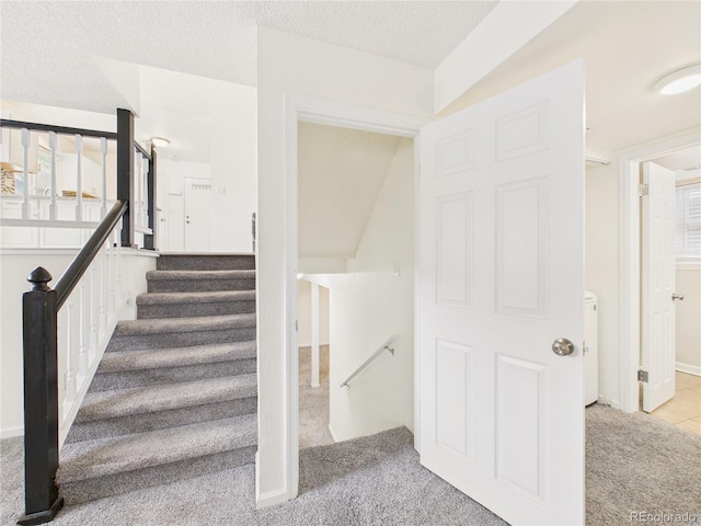 stairway with a textured ceiling and carpet floors