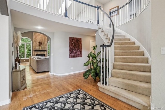 5564 S Jasper Way, Centennial, CO 80015 - entrance foyer with a brick fireplace, wood finished floors, arched walkways, stairs, and a high ceiling