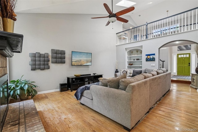 5564 S Jasper Way, Centennial, CO 80015 - living area with ceiling fan, arched walkways, built in shelves, wood finished floors, and high vaulted ceiling
