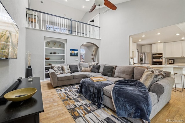 5564 S Jasper Way, Centennial, CO 80015 - living area with a ceiling fan, light wood finished floors, recessed lighting, arched walkways, and a towering ceiling