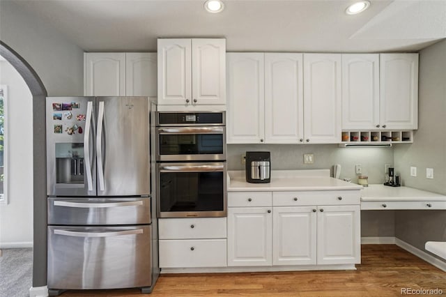 5564 S Jasper Way, Centennial, CO 80015 - kitchen featuring appliances with stainless steel finishes, arched walkways, white cabinetry, light countertops, and recessed lighting