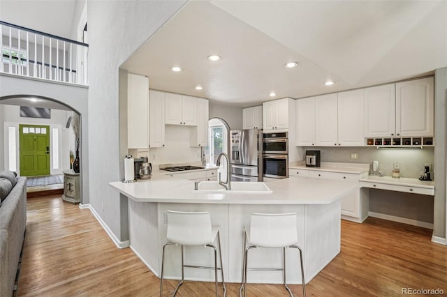 5564 S Jasper Way, Centennial, CO 80015 - kitchen featuring arched walkways, a peninsula, a breakfast bar area, stainless steel appliances, and light wood-style flooring