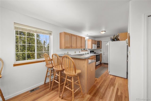 266 Gap Rd, Black Hawk, CO 80422 - kitchen featuring white appliances, light wood-style flooring, a peninsula, a breakfast bar, and glass insert cabinets
