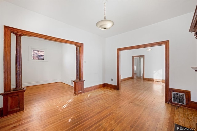 empty room with ornate columns and light hardwood / wood-style flooring