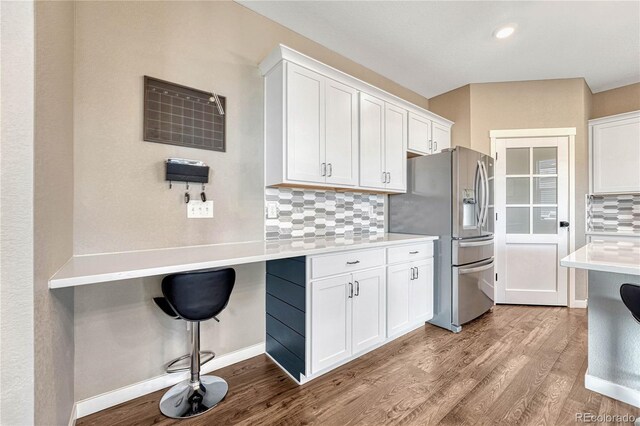 kitchen with backsplash, white cabinets, stainless steel refrigerator with ice dispenser, and wood finished floors