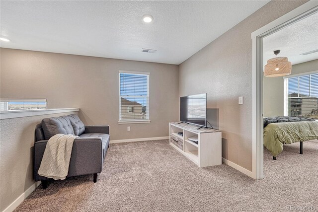 living area with light carpet, baseboards, visible vents, and a textured ceiling