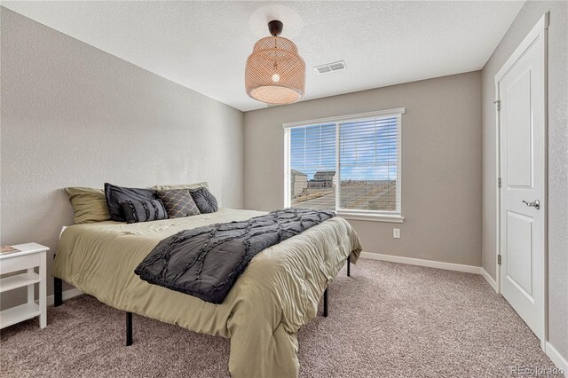 bedroom featuring carpet, visible vents, a textured wall, a textured ceiling, and baseboards