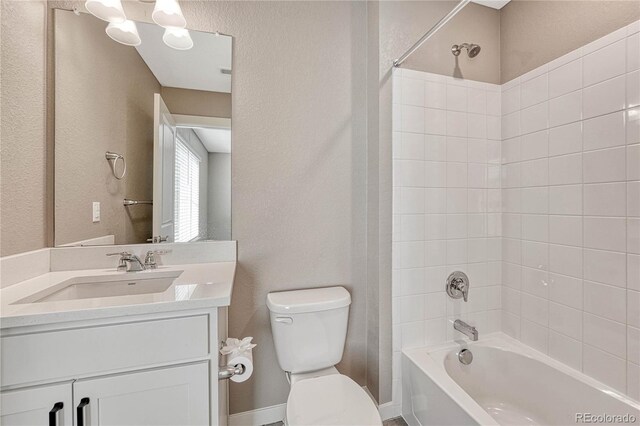 bathroom featuring toilet, a textured wall, bathtub / shower combination, and vanity