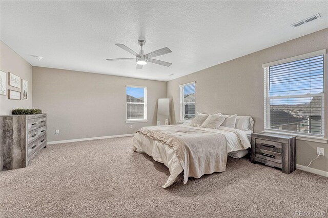 carpeted bedroom featuring a ceiling fan, visible vents, and a textured ceiling