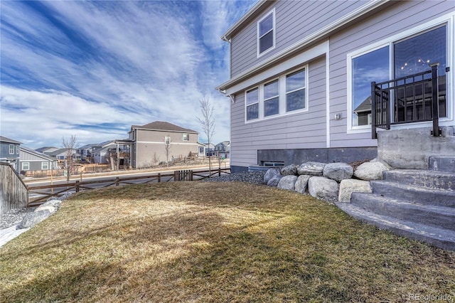 view of side of home with a residential view, a yard, and fence