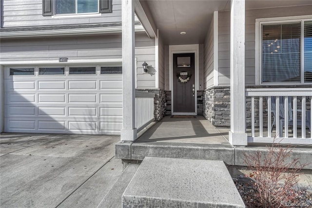 property entrance featuring stone siding, an attached garage, and concrete driveway