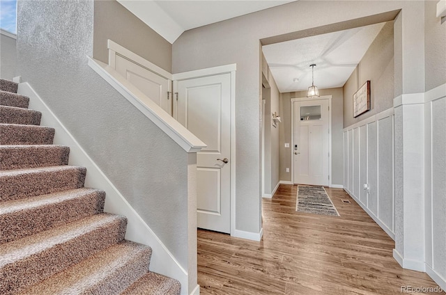 foyer entrance featuring stairs, baseboards, and wood finished floors