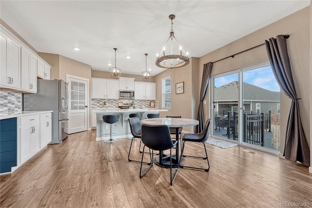 dining space featuring light wood-style floors and an inviting chandelier