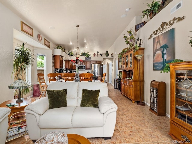 living room featuring light tile patterned flooring, a chandelier, and vaulted ceiling