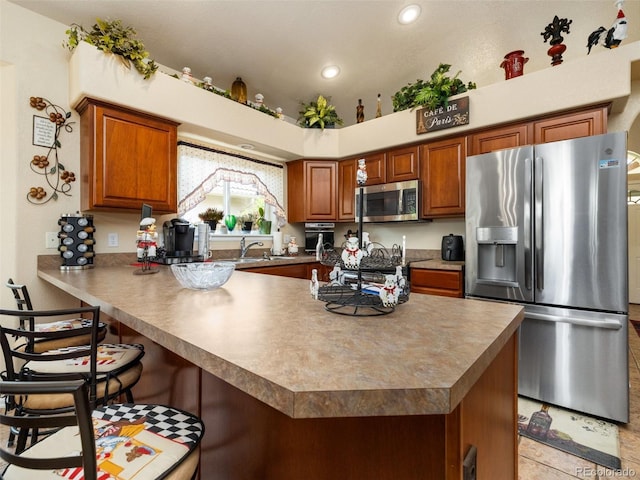 kitchen with sink, kitchen peninsula, stainless steel appliances, and a breakfast bar area