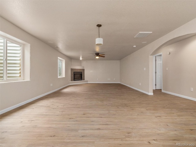 unfurnished living room with a textured ceiling, light hardwood / wood-style floors, ceiling fan, and a premium fireplace