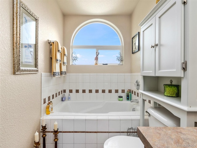 bathroom featuring a textured ceiling, vanity, and tiled tub