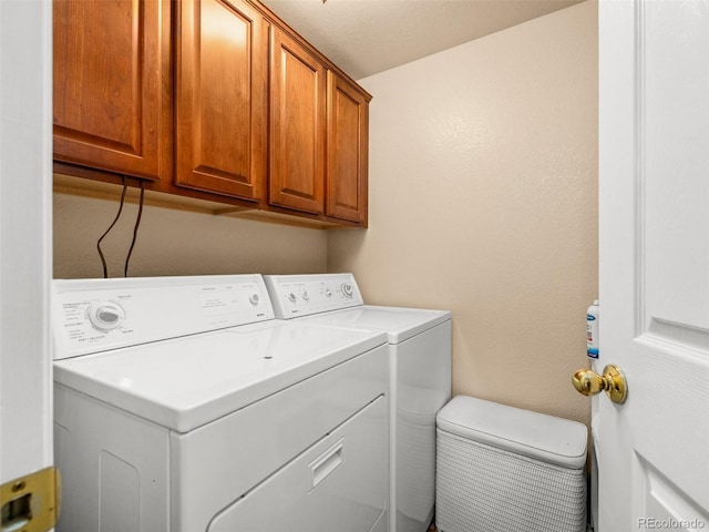 washroom featuring cabinets, a textured ceiling, and washing machine and clothes dryer