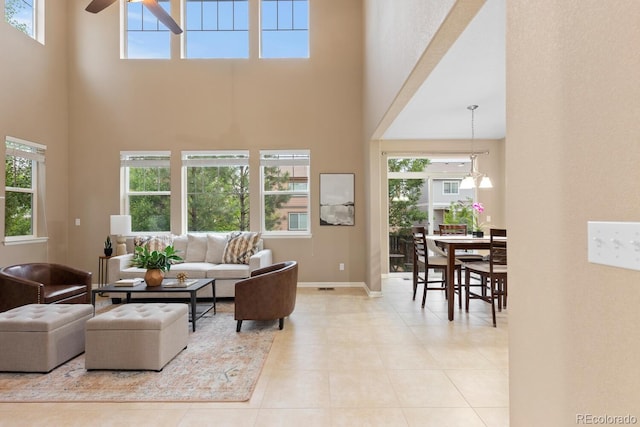 living room featuring a high ceiling, a ceiling fan, plenty of natural light, baseboards, and tile patterned flooring