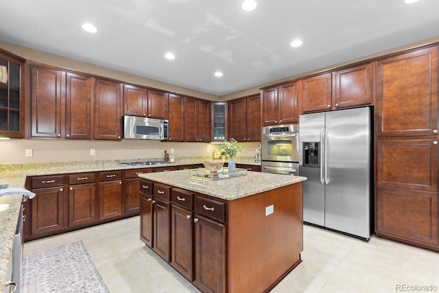 kitchen featuring appliances with stainless steel finishes, a center island, light stone countertops, recessed lighting, and glass insert cabinets