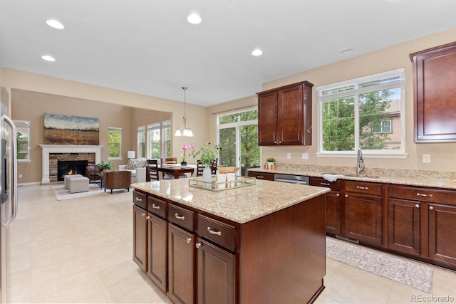 kitchen featuring a sink, open floor plan, light stone counters, a center island, and recessed lighting
