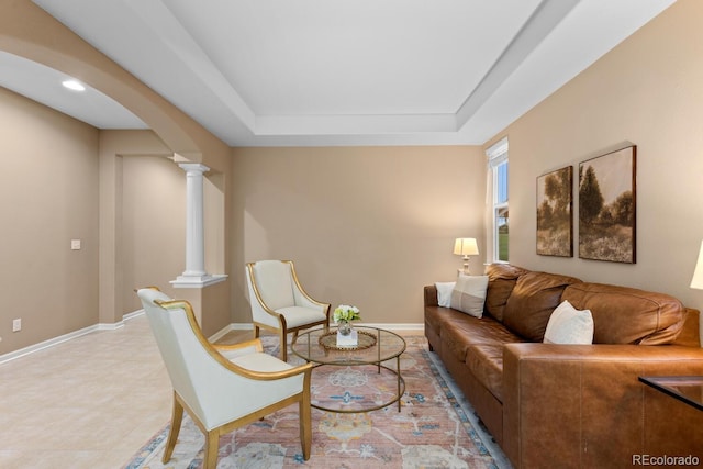 living room with decorative columns, arched walkways, a raised ceiling, and baseboards