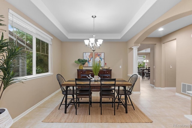 dining area with ornate columns, arched walkways, a raised ceiling, a chandelier, and baseboards