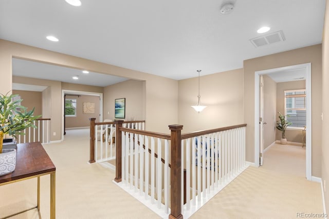 hall with an upstairs landing, light colored carpet, recessed lighting, and baseboards