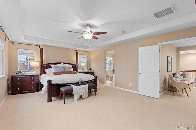 carpeted bedroom featuring a raised ceiling, multiple windows, and baseboards