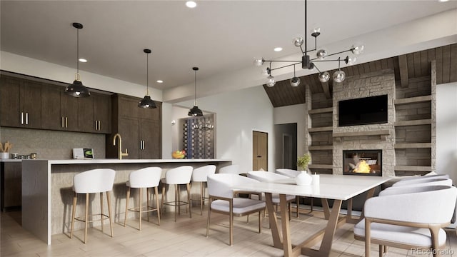 kitchen featuring a kitchen breakfast bar, dark brown cabinetry, a fireplace, and decorative light fixtures